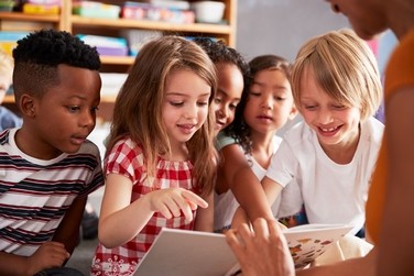 Leerlingen en een leerkracht kijken in een boek