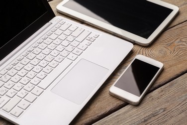 Een laptop en tablet en mobiele telefoon liggend op een tafel